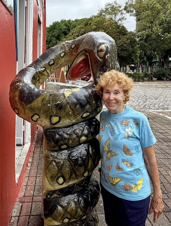 Adventures for Solo Travelers community member Wanda Ross poses with a giant snake sculpture in Brazil during a fun small group tour for solo travelers.