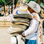 Street vendor selling traditional Sombrero Vueltiao hats in Medellín, Colombia, during an Adventures for Solo Travelers small group tour exploring Colombian culture and local markets.